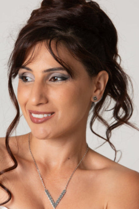 Woman with styled hair and jewelry against a plain background